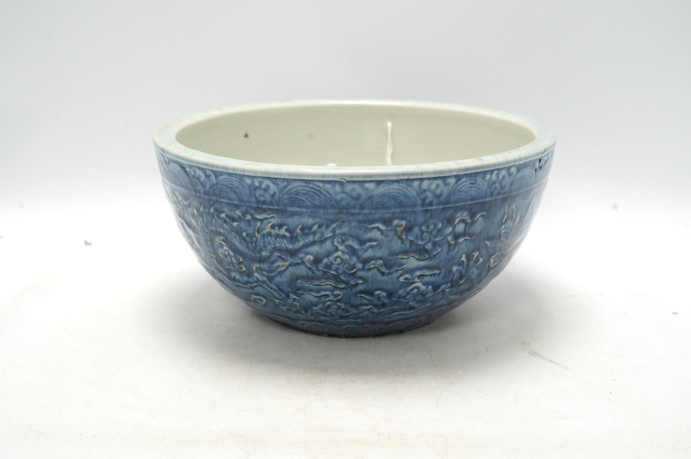 A large Chinese blue and white ‘dragon’ bowl decorated in low relief, 28cm in diameter. Condition - good